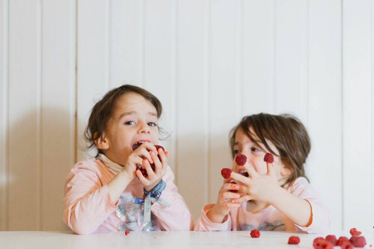 Cute Sisters Eating Raspberries. A good example of gluten-free snacks for kids
